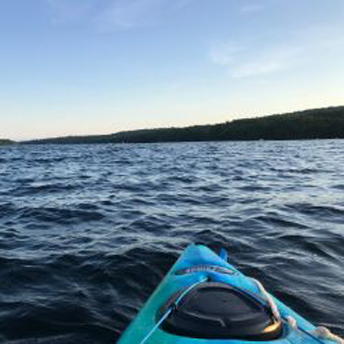 Shot of the horizon from the water, front tip of a kayak in the foreground